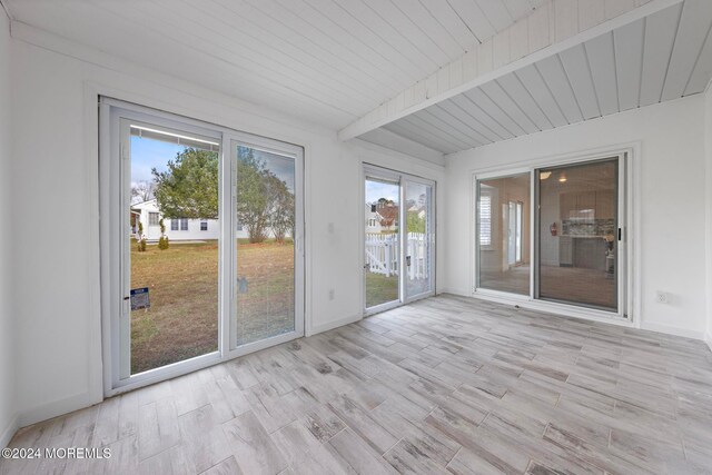 unfurnished sunroom featuring beamed ceiling and wood ceiling