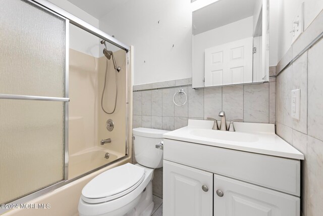 full bathroom featuring vanity, toilet, tile walls, and bath / shower combo with glass door