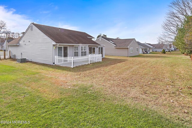 back of property featuring central AC and a lawn