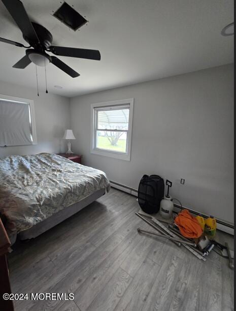 bedroom with hardwood / wood-style floors, a baseboard radiator, and ceiling fan