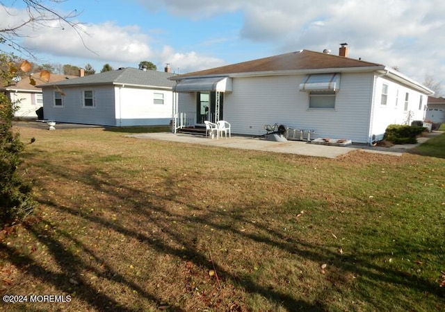 rear view of property featuring a lawn and a patio area