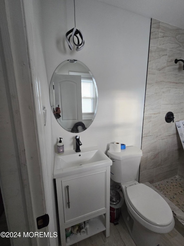 bathroom with vanity, toilet, and a tile shower