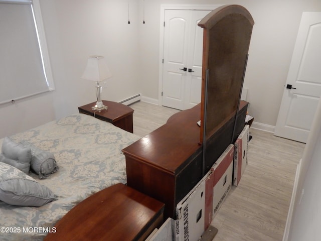 bedroom featuring a baseboard heating unit and light wood-type flooring