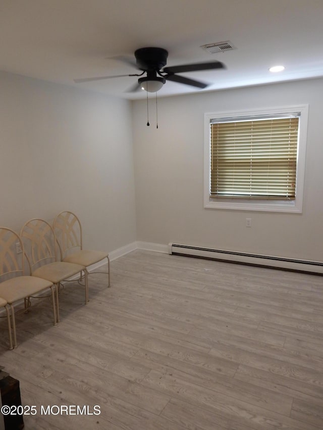 unfurnished room featuring ceiling fan, a baseboard radiator, and light wood-type flooring