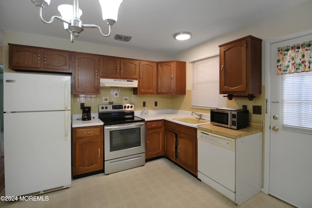 kitchen with decorative backsplash, stainless steel appliances, sink, a notable chandelier, and hanging light fixtures