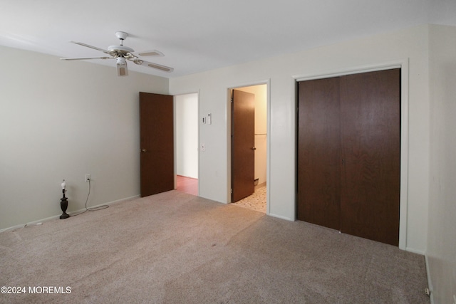 unfurnished bedroom with light colored carpet, a closet, and ceiling fan