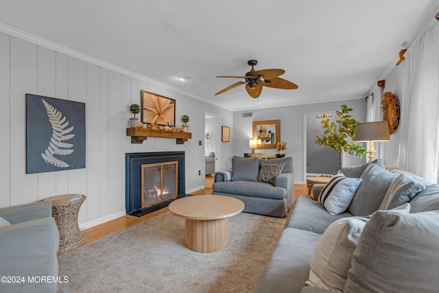 living room featuring hardwood / wood-style flooring, ceiling fan, and crown molding