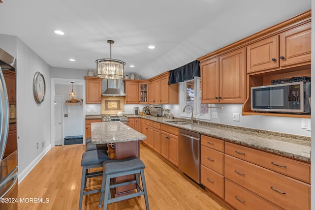 kitchen with a kitchen bar, light stone counters, light hardwood / wood-style floors, and appliances with stainless steel finishes