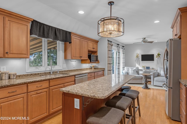 kitchen with a center island, ceiling fan with notable chandelier, sink, light wood-type flooring, and stainless steel appliances