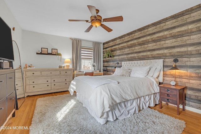 bedroom with wooden walls, light hardwood / wood-style flooring, and ceiling fan