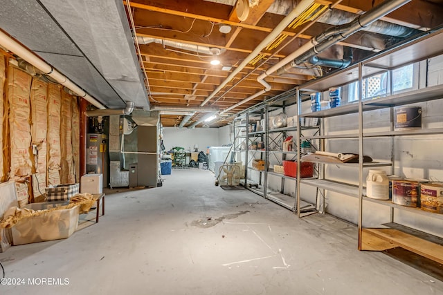 basement featuring gas water heater, heating unit, and washer / clothes dryer