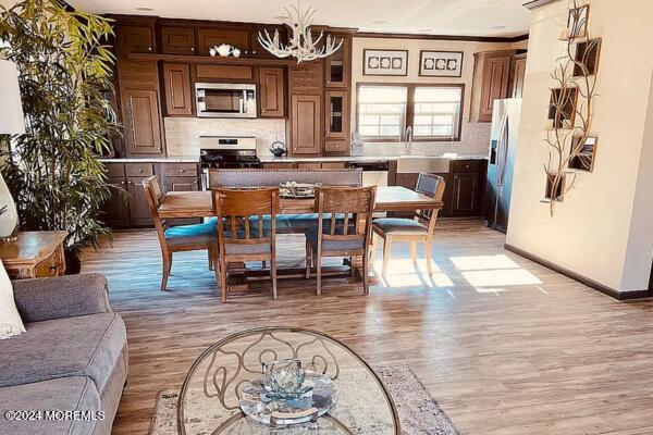 dining space featuring a notable chandelier, sink, light wood-type flooring, and ornamental molding