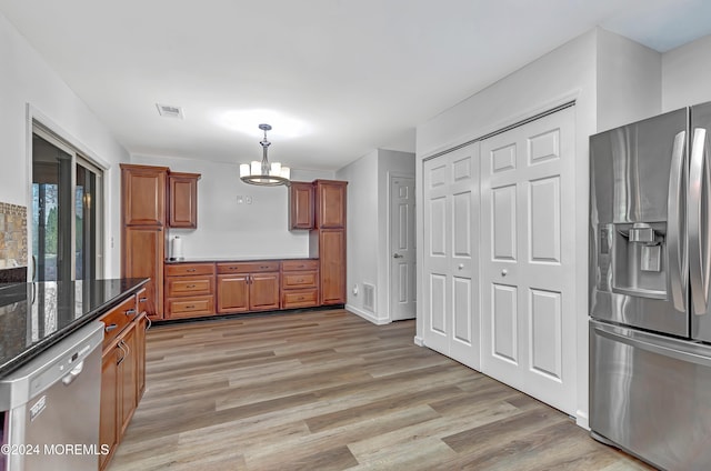 kitchen with pendant lighting, an inviting chandelier, light hardwood / wood-style flooring, dark stone countertops, and appliances with stainless steel finishes