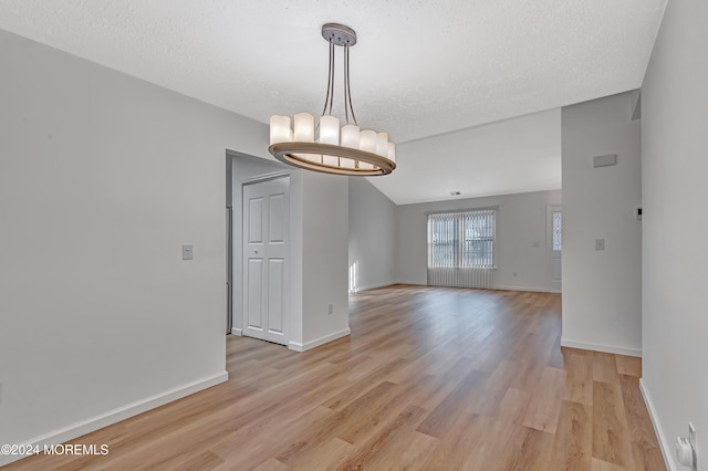 unfurnished room featuring vaulted ceiling, light hardwood / wood-style flooring, and a textured ceiling