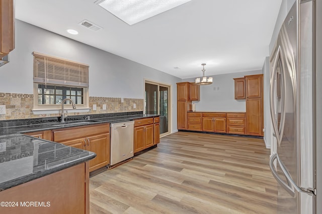 kitchen featuring sink, decorative light fixtures, decorative backsplash, appliances with stainless steel finishes, and light wood-type flooring