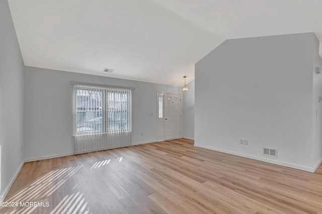 unfurnished room with lofted ceiling and light hardwood / wood-style flooring