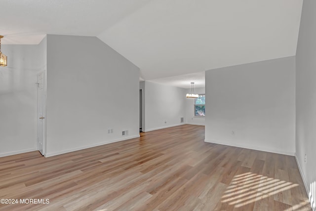 interior space featuring light wood-type flooring, an inviting chandelier, and vaulted ceiling