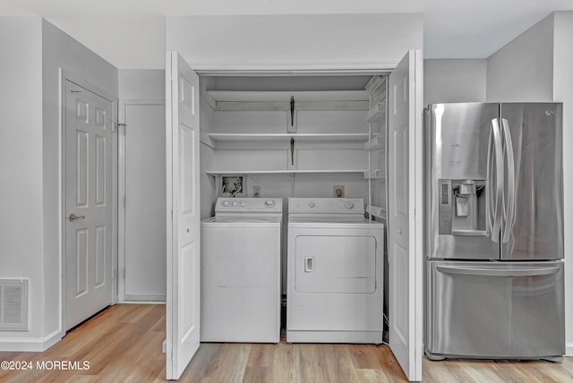 clothes washing area with light hardwood / wood-style floors and washer and clothes dryer