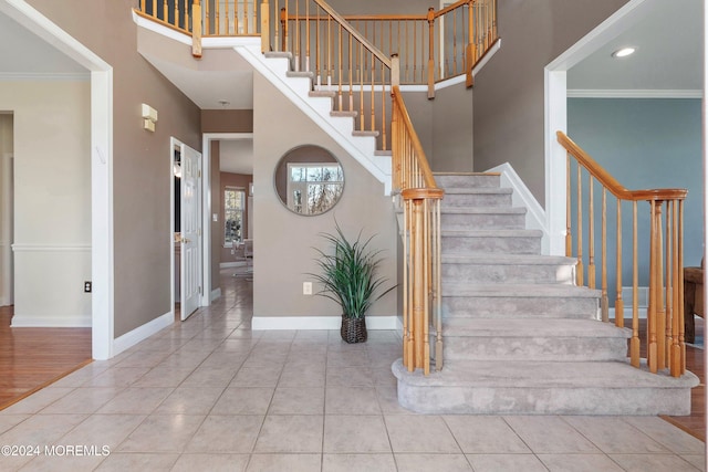 staircase featuring wood-type flooring, a towering ceiling, and ornamental molding