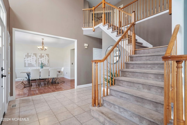 stairs featuring a towering ceiling, a chandelier, and hardwood / wood-style flooring