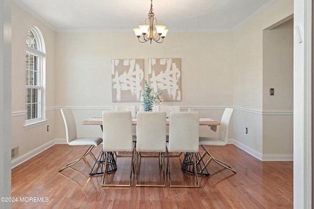 dining space with ornamental molding, a notable chandelier, and hardwood / wood-style flooring