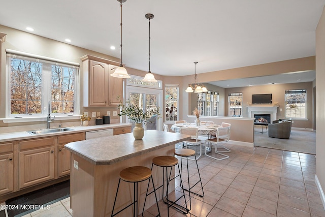 kitchen with sink, light brown cabinets, a notable chandelier, white dishwasher, and decorative light fixtures