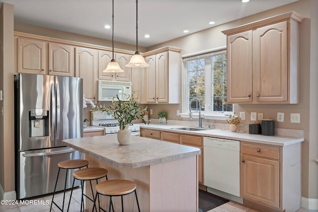 kitchen featuring white appliances, sink, and light brown cabinetry