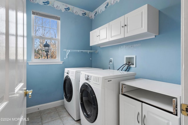 clothes washing area with cabinets, light tile patterned floors, and washer and dryer