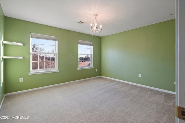 carpeted spare room with a chandelier