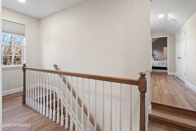 stairway with wood-type flooring and lofted ceiling