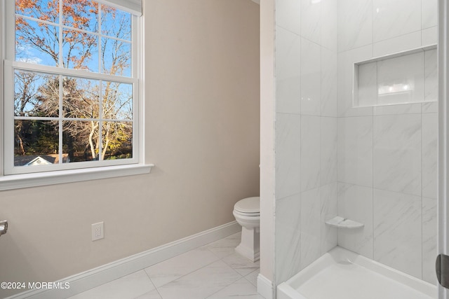 bathroom featuring a tile shower and toilet