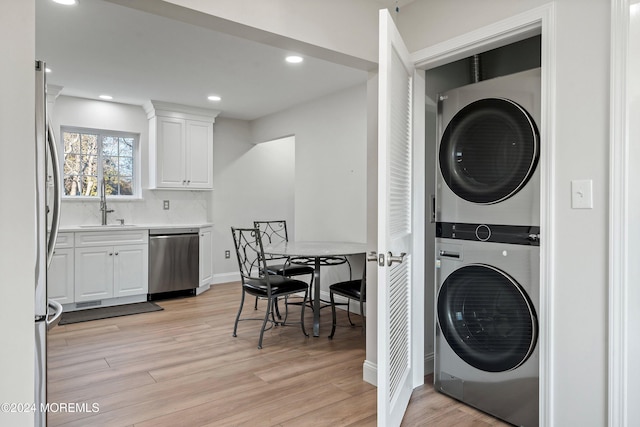 laundry area with sink, stacked washer and dryer, and light wood-type flooring