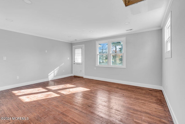 empty room featuring wood-type flooring and crown molding