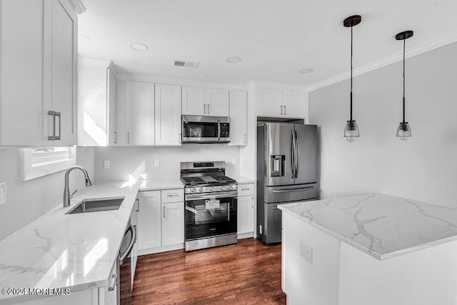 kitchen with sink, dark wood-type flooring, pendant lighting, white cabinets, and appliances with stainless steel finishes