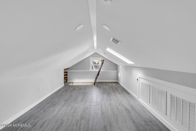 additional living space with wood-type flooring and vaulted ceiling with skylight