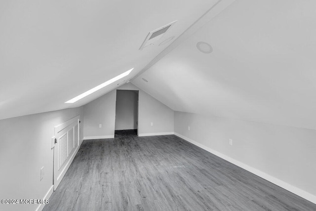 additional living space featuring dark hardwood / wood-style flooring and lofted ceiling with skylight