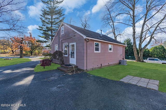 view of property exterior featuring central air condition unit and a lawn