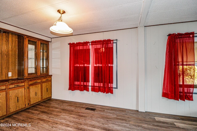 unfurnished dining area with dark hardwood / wood-style floors and wooden walls