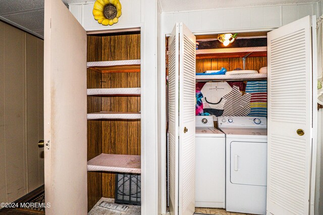 laundry area featuring separate washer and dryer and wood walls