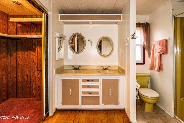 bathroom with vanity, toilet, wood-type flooring, and wooden walls