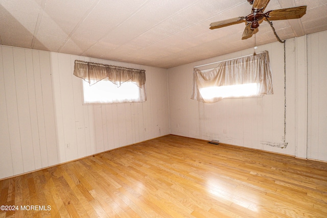 spare room with wooden walls, hardwood / wood-style floors, and ceiling fan