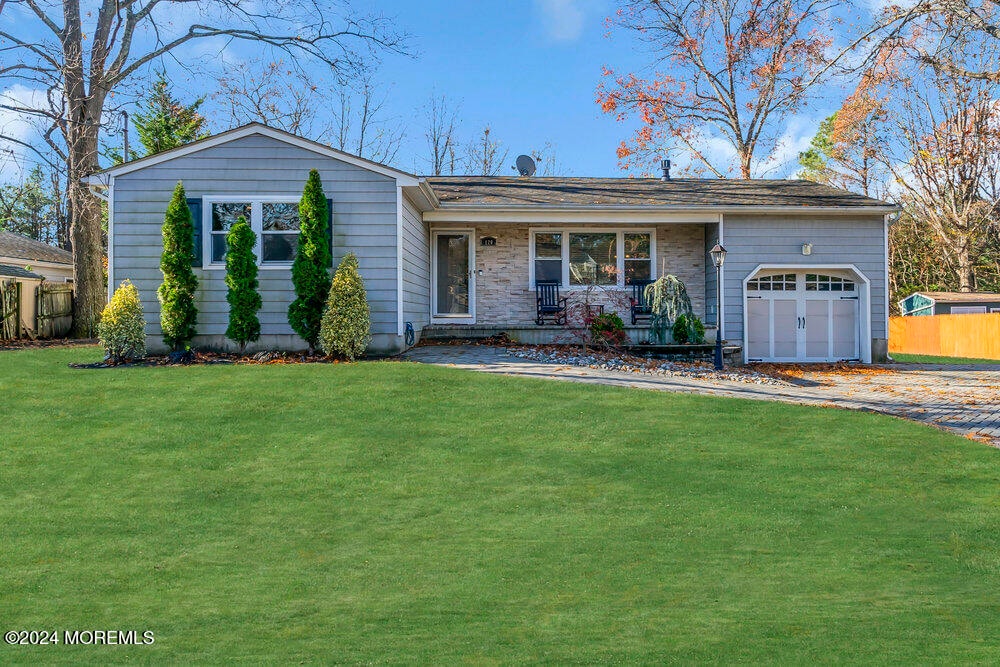 single story home with a porch, a garage, and a front yard