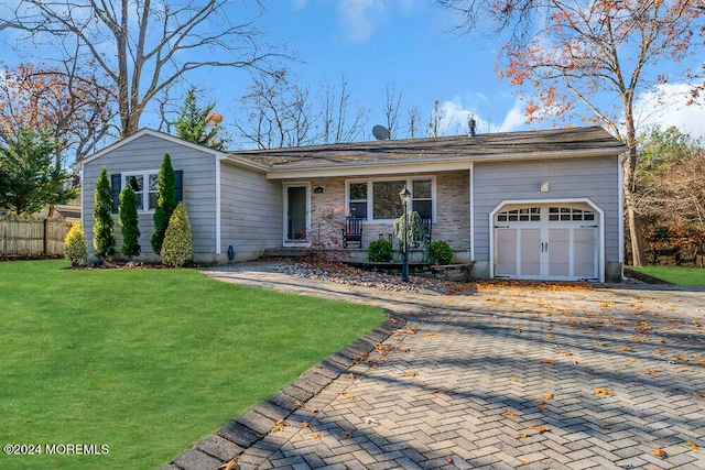 ranch-style home with a front lawn, covered porch, and a garage