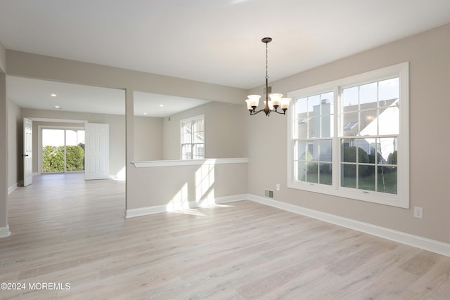 empty room with light hardwood / wood-style flooring and a chandelier