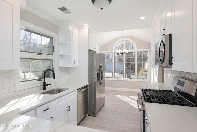 kitchen featuring appliances with stainless steel finishes, backsplash, sink, white cabinetry, and lofted ceiling