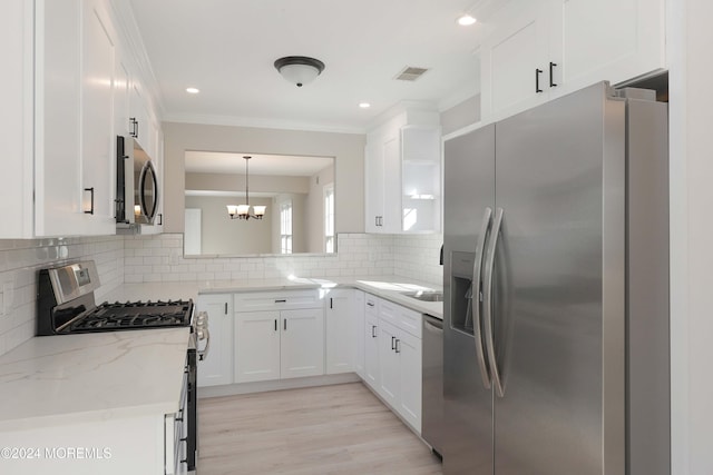 kitchen with tasteful backsplash, light stone counters, appliances with stainless steel finishes, white cabinets, and light wood-type flooring