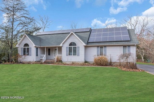 view of front of property featuring covered porch, a front yard, and solar panels