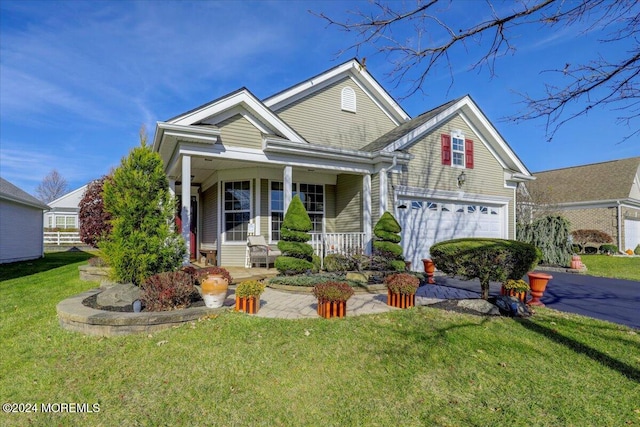 view of front of house with covered porch, a garage, and a front lawn