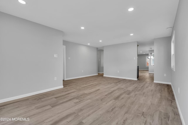 unfurnished room featuring a notable chandelier and light hardwood / wood-style floors