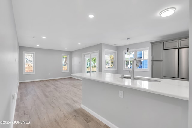 kitchen featuring stainless steel fridge, a wealth of natural light, gray cabinetry, and sink